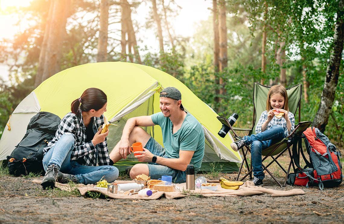 A family camping in the woods after buying the perfect camping tent A family camping in the woods after buying the perfect camping tent